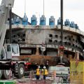 Crews lift Scuffed and Rusty Disc-Shaped Front End of Broken Tunnel-Boring Machi